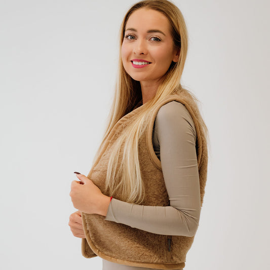 Blond kvinne viser brun ullvest fra siden.